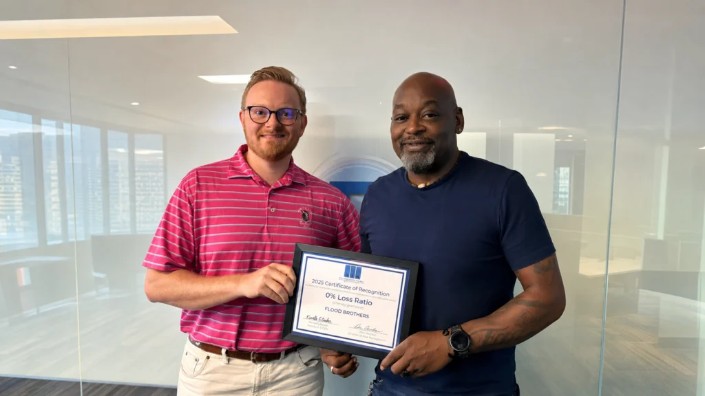 Flood Brothers team holding the 2025 Certificate of Recognition for a 0% loss ratio
